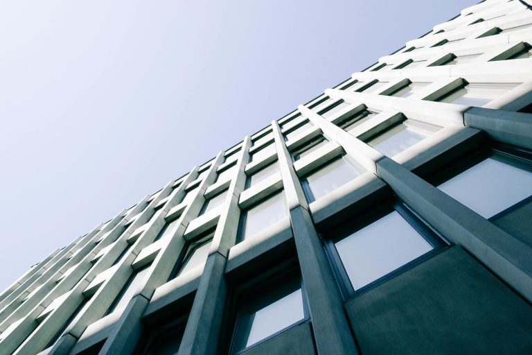 Low angle view of a modern skyscraper with geometric design and reflective windows.